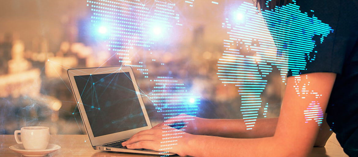 Pessoa ao notebook com mapa-múndi e foco em Protocolo de Madri.