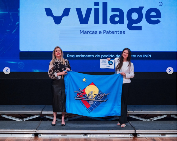 Representante da VILAGE com bandeira, homenageando jovem inventor da Mostratec